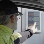 Person mit Basecap bedient Touchscreen mit Sprachauswahl